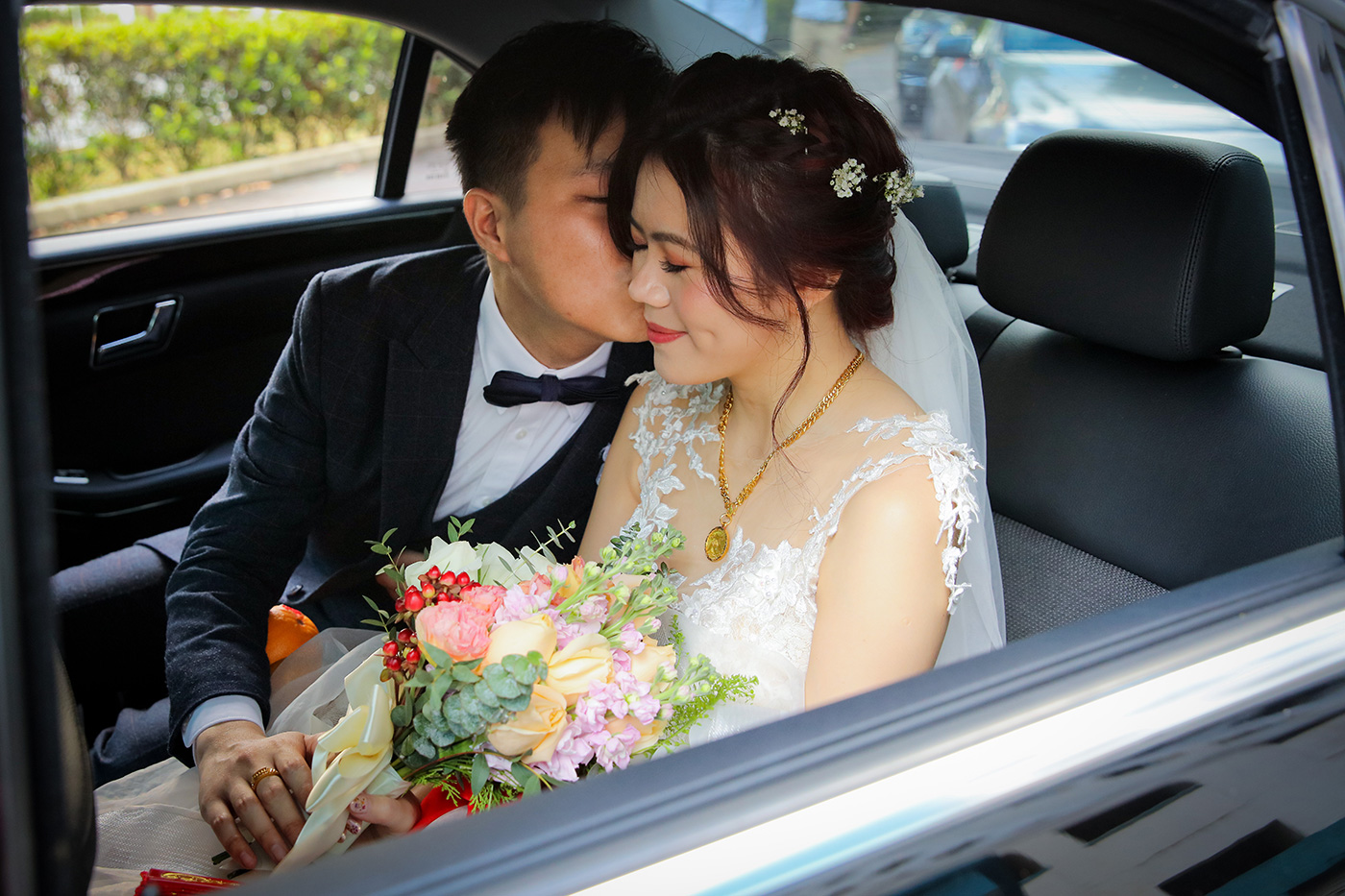 Bride and groom intimate moment in wedding car with bouquet Singapore