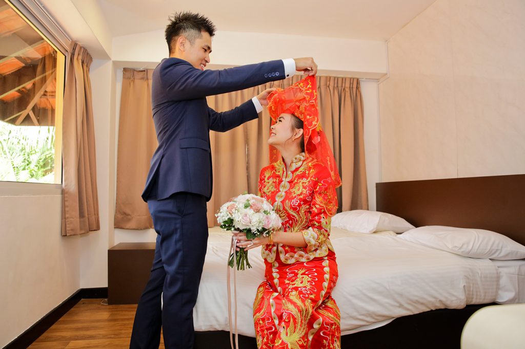 Bride on hotel bed with white gown and wedding bouquet during bridal portrait session