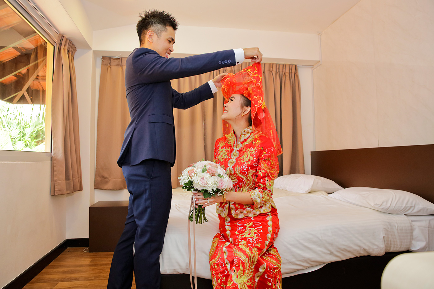Bride on hotel bed with white gown and wedding bouquet during bridal portrait session