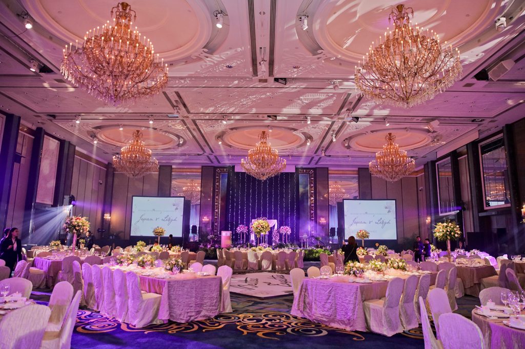 Purple-lit wedding banquet ballroom setup with chandeliers at Singapore hotel