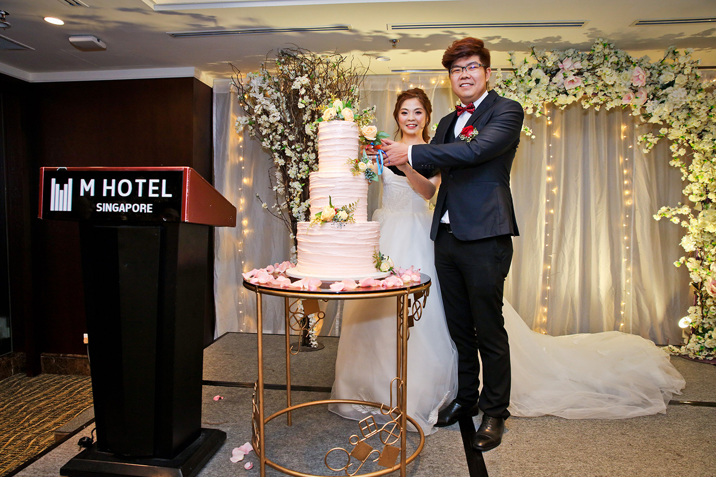 Wedding cake cutting ceremony at M Hotel Singapore with elegant floral backdrop