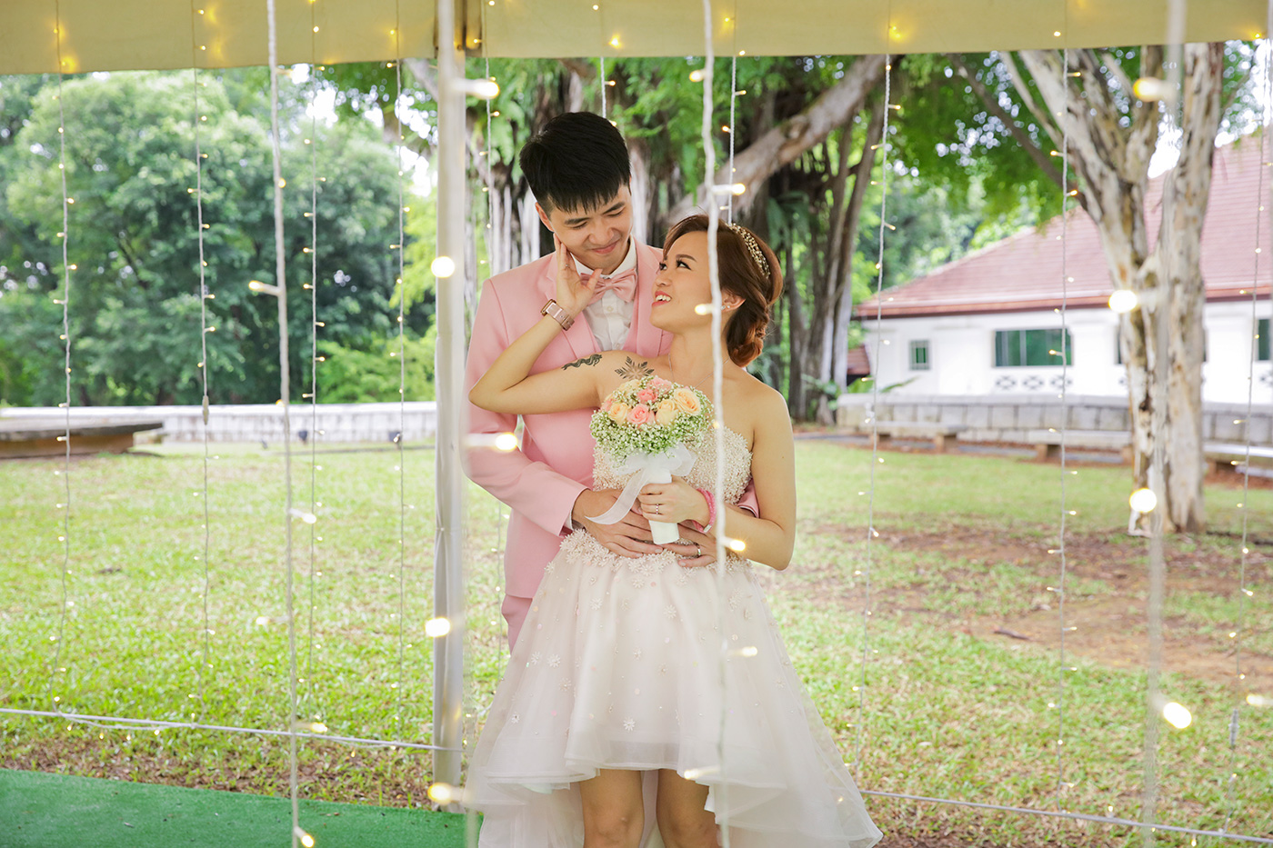 Bride and groom under fairy lights at outdoor garden pavilion Singapore wedding