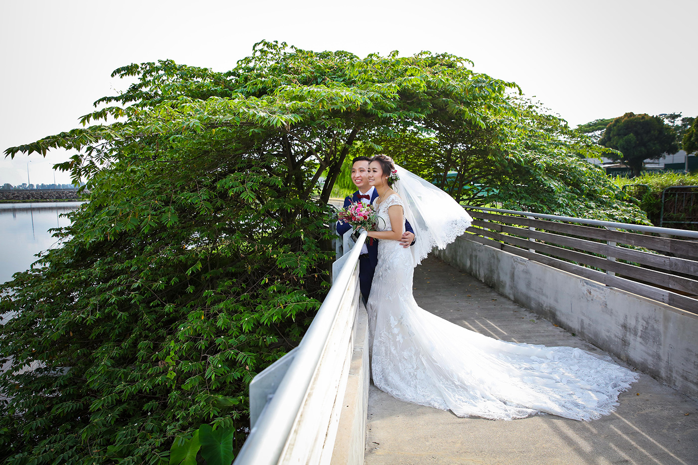 Wedding couple portrait on waterside bridge with lush rain tree in Singapore park