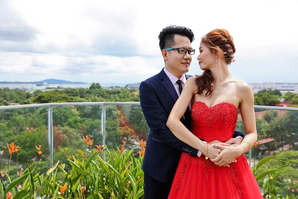 Wedding couple on rooftop with Singapore panoramic skyline bride in red evening gown
