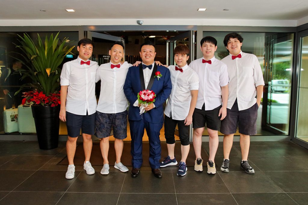 Groomsmen in white shirts and red bow ties group photo with groom in navy suit